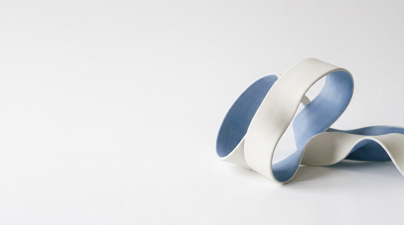 Sculptural white and blue ribbon form on a bright studio background